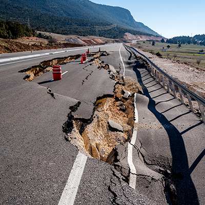 Route goudronnée effondrée et fissures sur le bord de la route