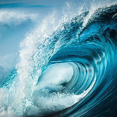 Détail en gros plan d'une puissante vague bleu sarcelle déferlant en pleine mer par un après-midi ensoleillé.